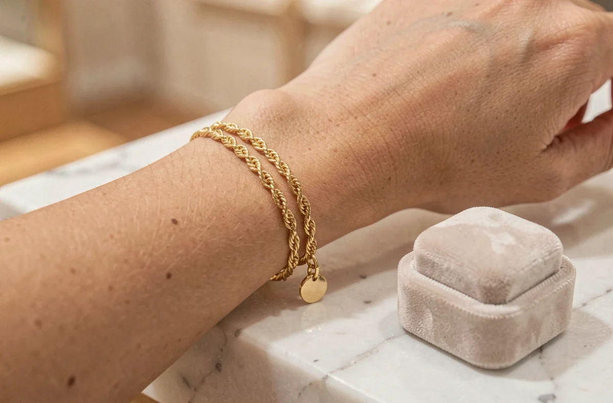 Bracelet femme en or fin avec chaîne torsadée et pendentif posé sur un écrin en velours et marbre blanc