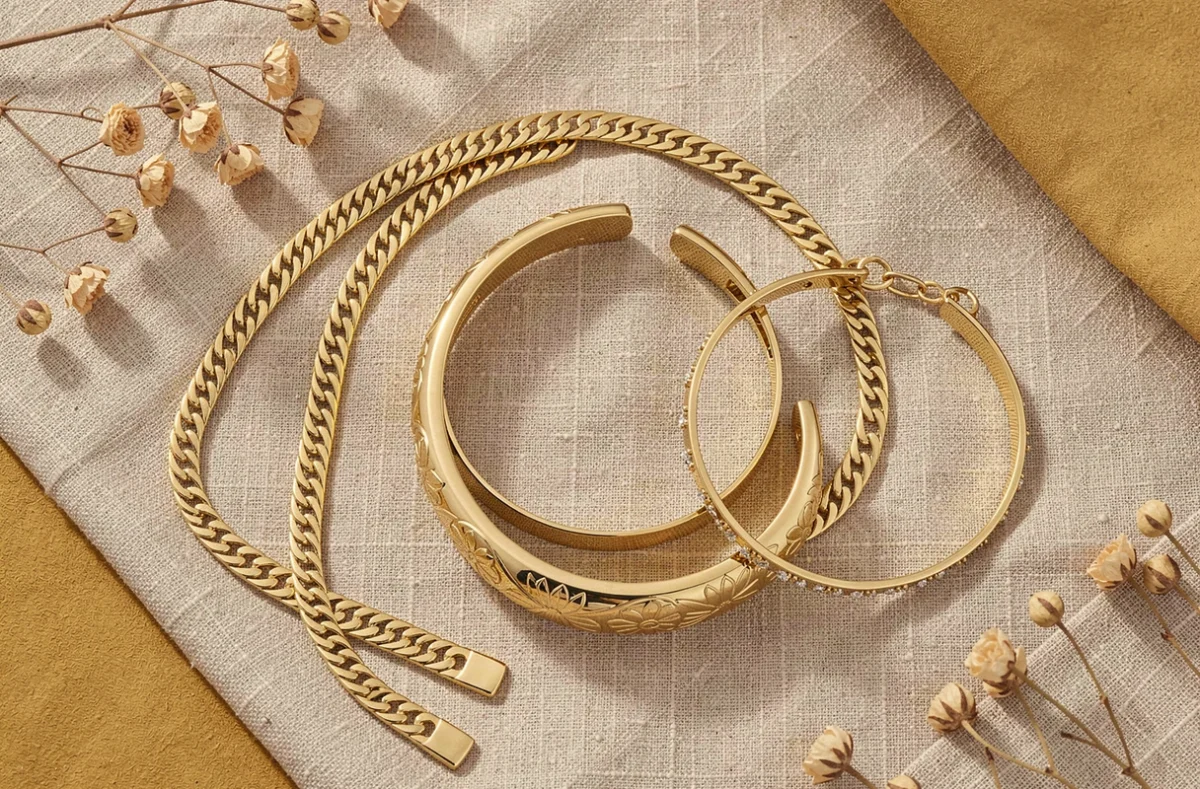 Flat lay de plusieurs bracelets femme en or sur tissu lin texturé incluant chaîne, jonc et bracelet tennis